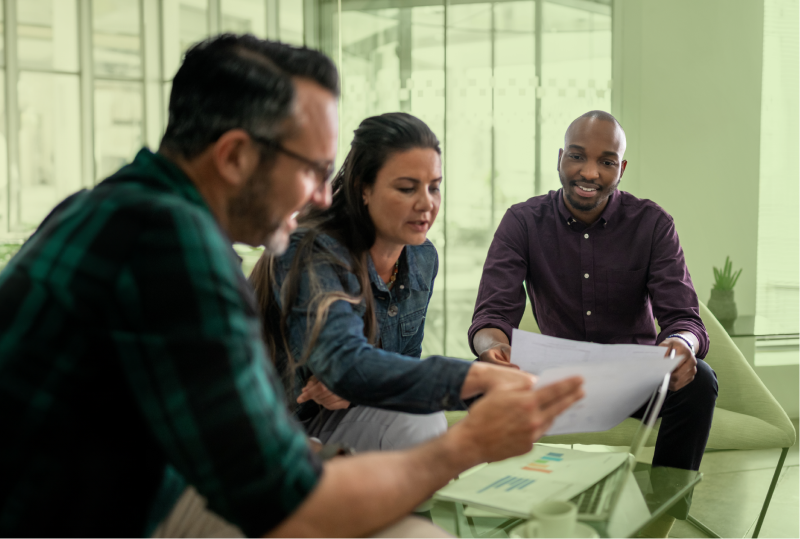 A pay transparency policy is being read by three happy employees sitting around a table